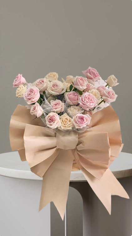 باکس گل رز پاپیونی با طراحی خاص وروبان بزرگ کرمی شامل دسته ای از رز های صورتی و کرم شیک