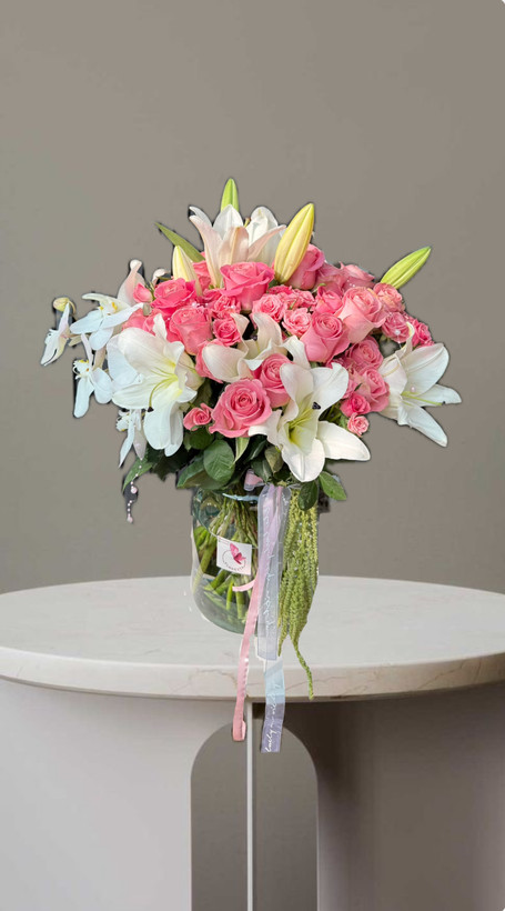 جار گل لوکس شیشه ای با گل رز هلندی و رز مینیاتوری صورتی و ارکیده و لیلیوم سفید و مروارید های صورتی