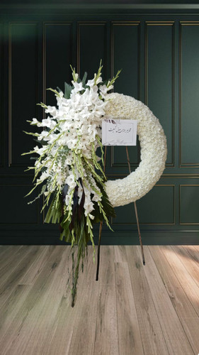 تاج گل تسلیت سفید با طراحی نیمدایرهای از گلهای گلایل و داوودی سفید مناسب مراسم ترحیم